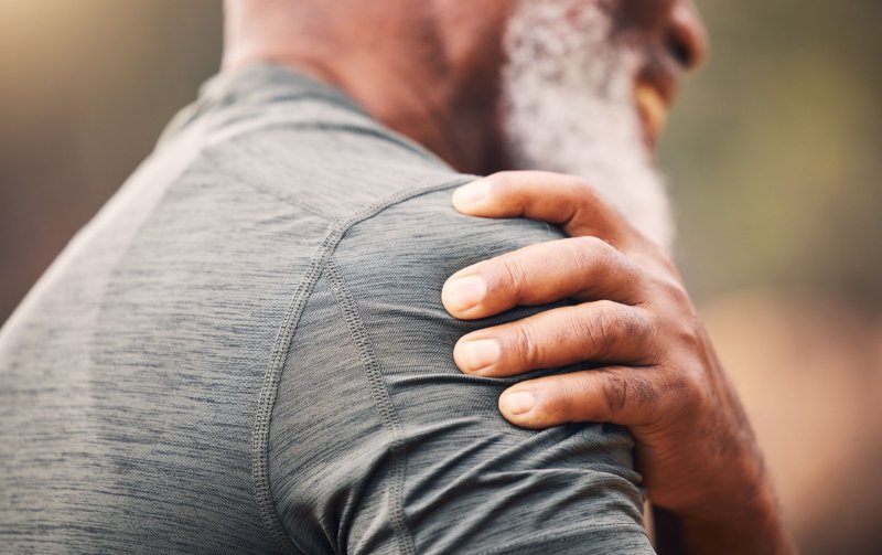 Man holding shoulder illustrating neck and joint pain relief treatment.