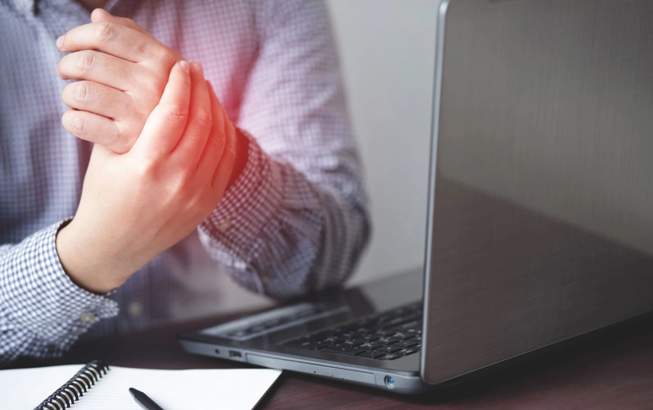 Person rubbing wrist experiencing pain and discomfort from computer work.