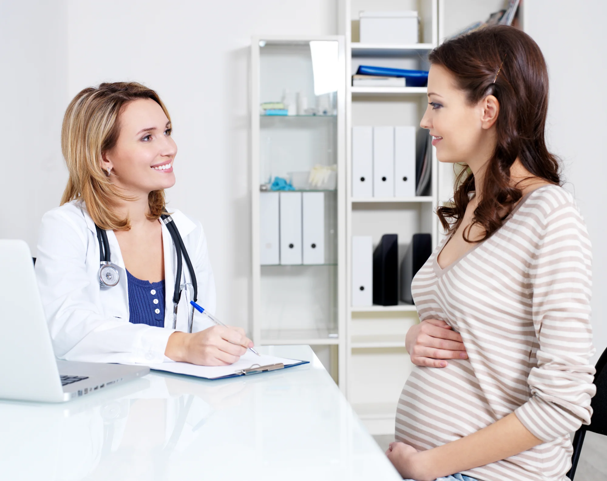 Pregnant woman consulting with chiropractor during prenatal care appointment.