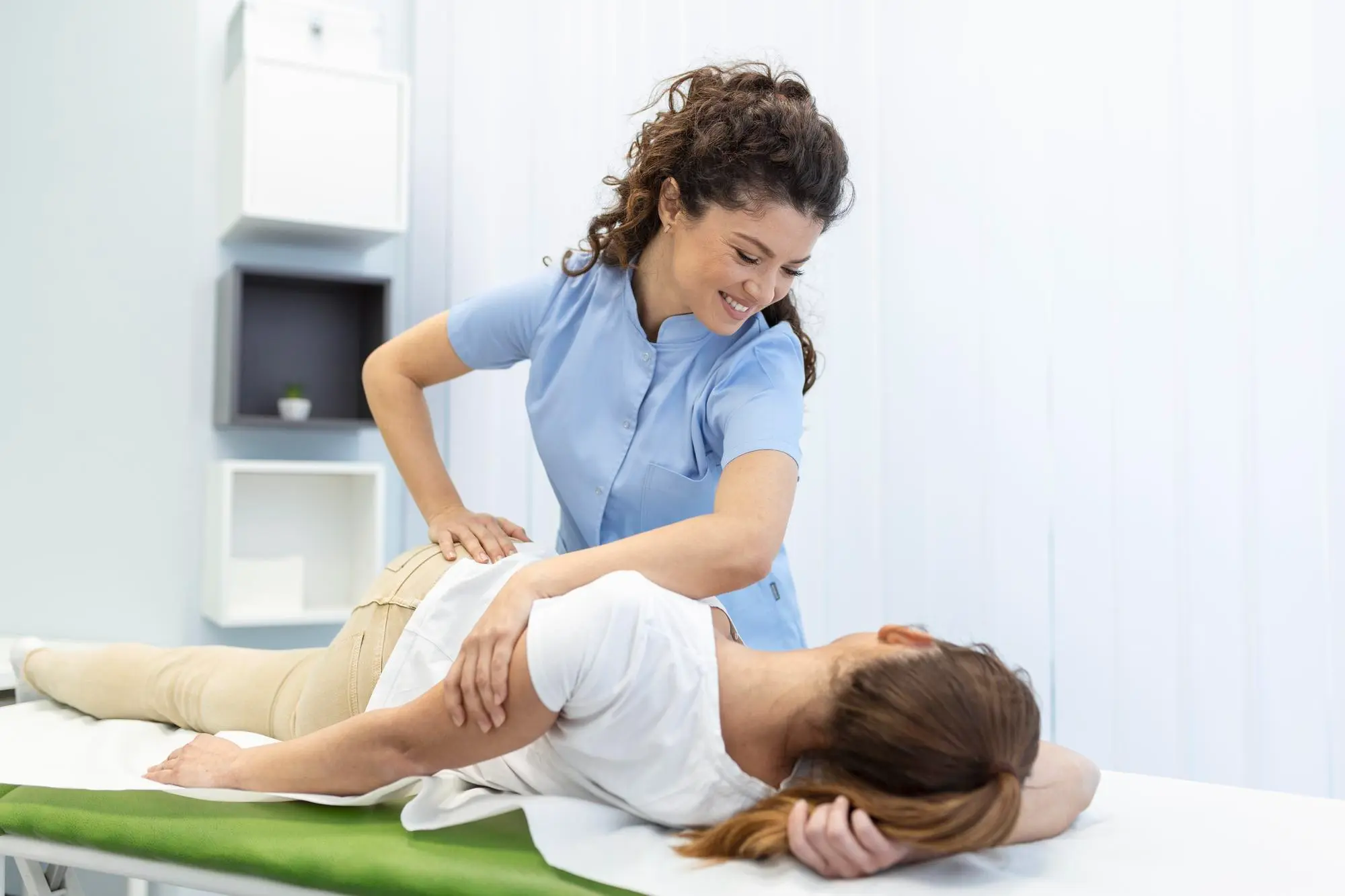Physical therapist providing back pain treatment and massage therapy to patient.