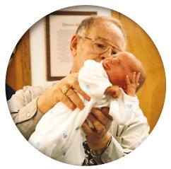 Dr. Clarence Gonstead holding a baby, illustrating patient care and the Gonstead Technique.