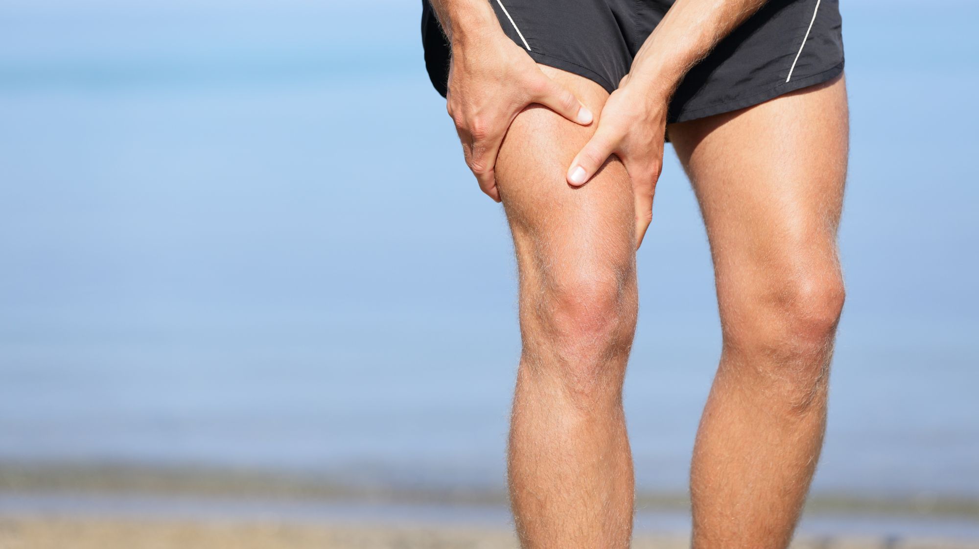 Man massaging his thigh illustrating muscle tension and pain relief with trigger point injections.