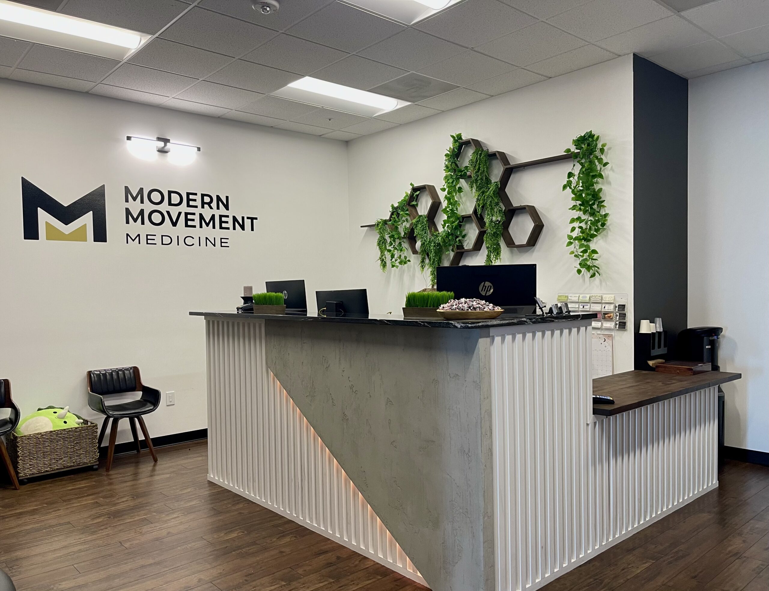 Modern Movement Medicine front desk and reception area with logo and greenery.