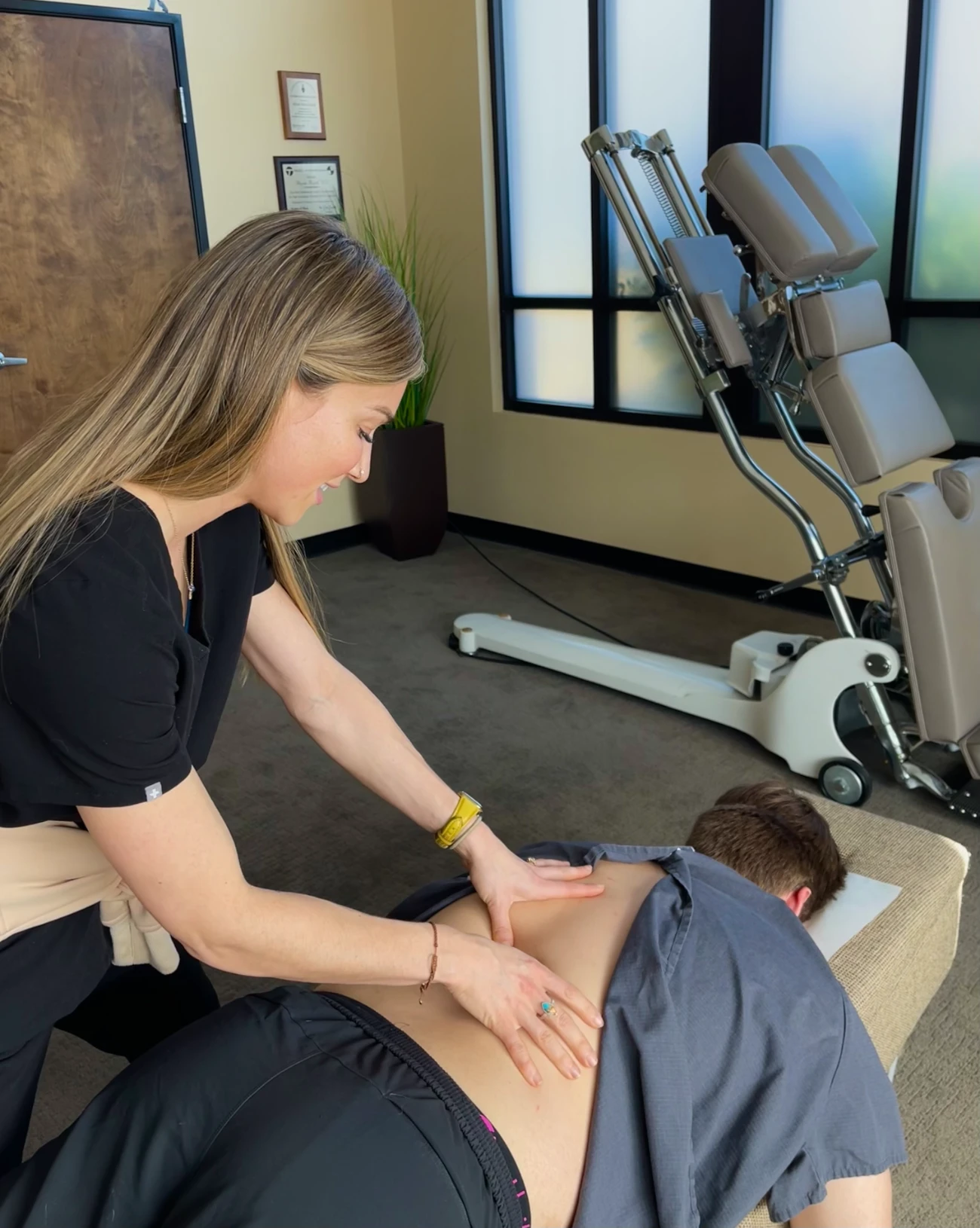 Chiropractor treating patient's back pain with specialized equipment at Modern Movement Medicine.
