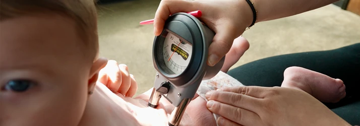 A chiropractic practitioner using a nervoscope on a baby's back
